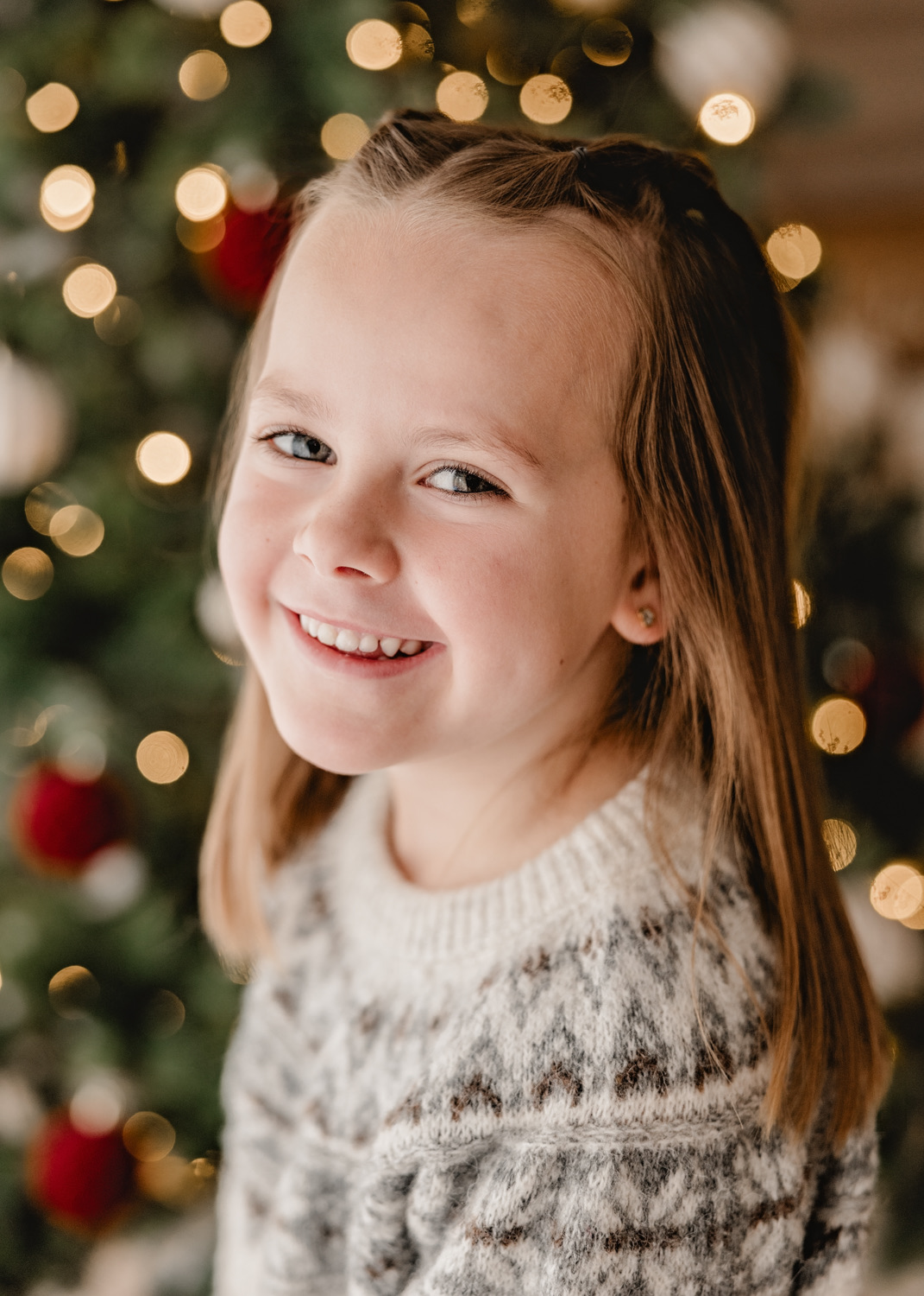 Natürliches Kinderportrait vor dem Weihnachtsbaum